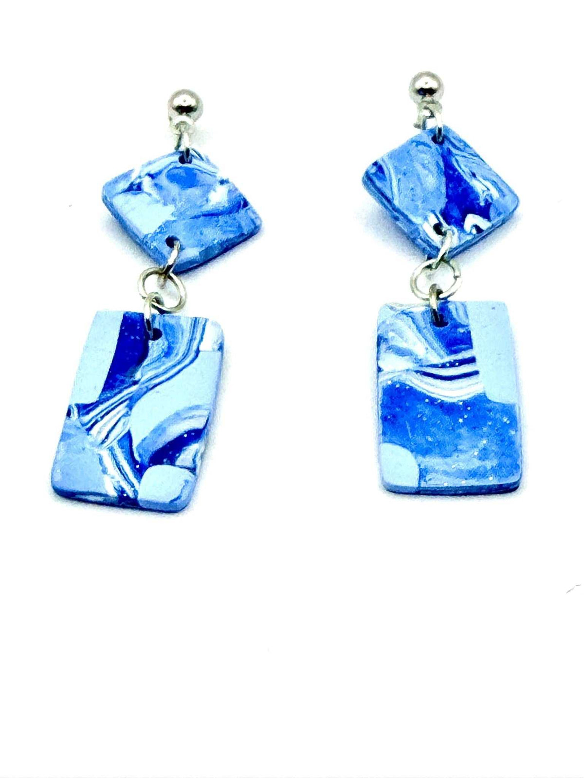 A pair of drop earrings featuring marbled blue and white resin pendants with silver-tone metal posts and balls, shown against a plain white background.