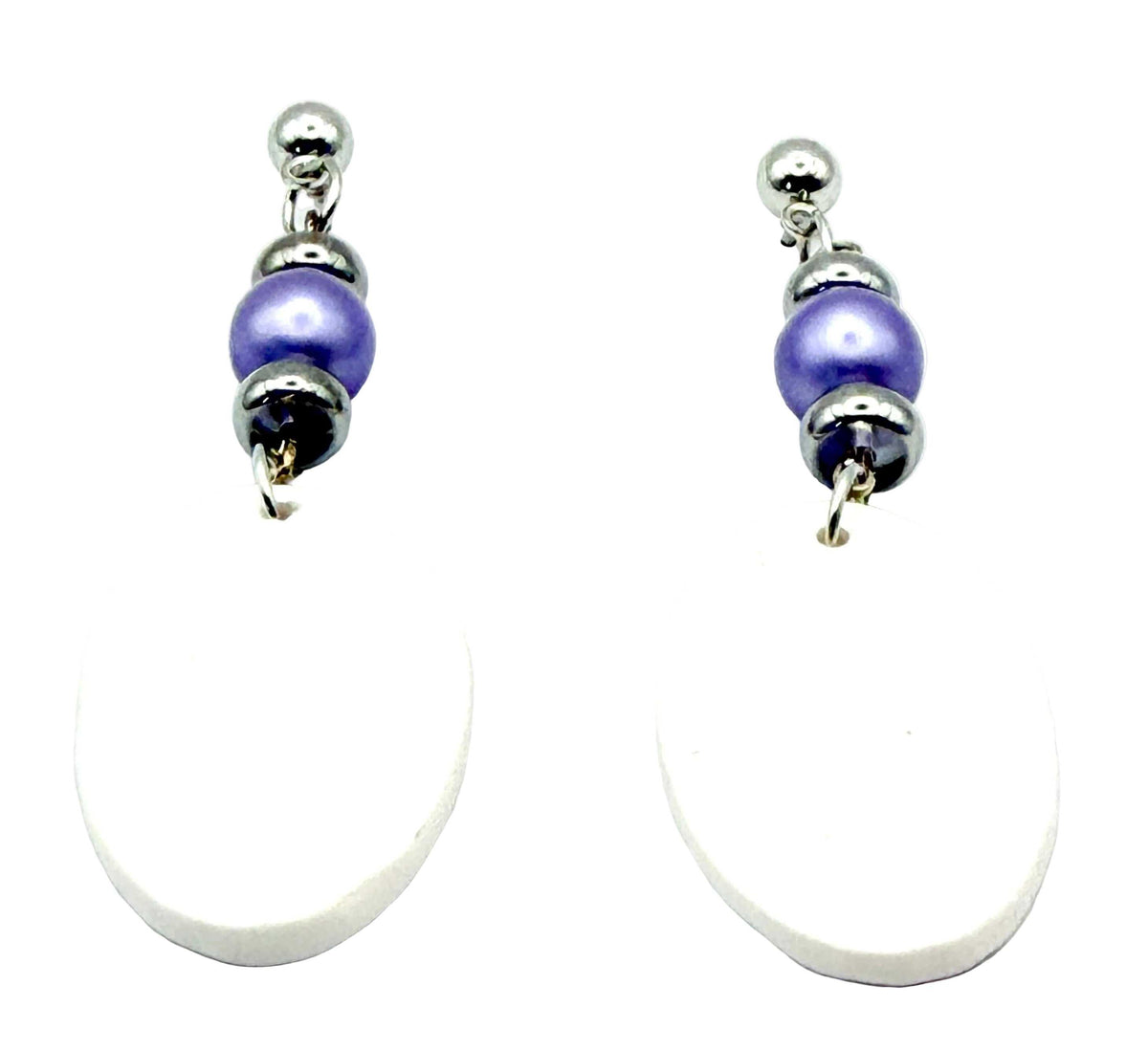 A pair of dangle earrings featuring large, flat white oval discs hanging from silver-toned posts that have a purple bead and a small black bead in between.
