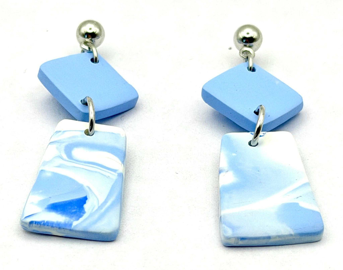 A pair of drop earrings featuring light blue and white marbled rectangular charms with silver ball studs, displayed on a clean white background.