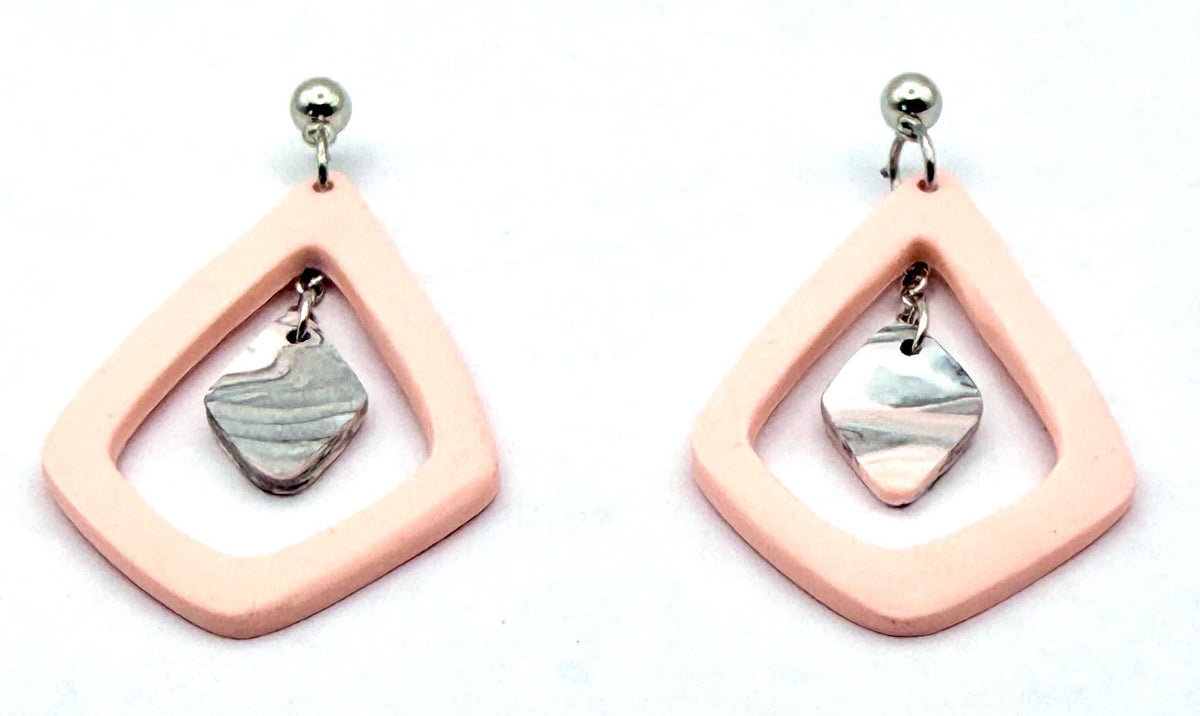 A pair of handmade dangle earrings featuring a peach-pink open geometric frame with a small silver-toned metal ball at the top and a marbled silver stone dangle inside, set against a plain white background.