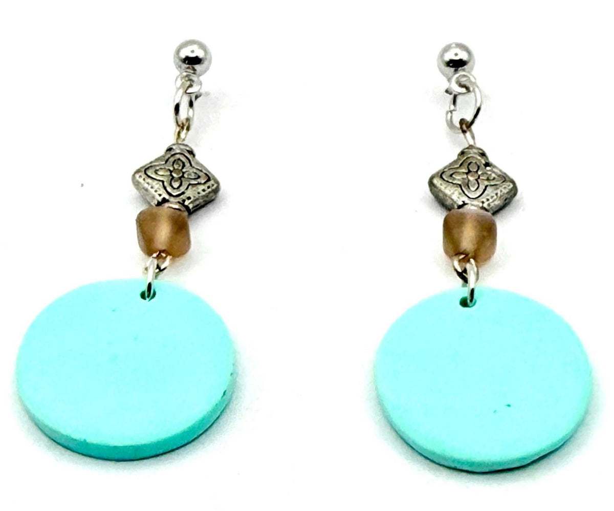 A pair of handmade dangle earrings featuring large light blue circular discs, small brown beads, and silver-toned metal accents, shown on a plain white background.