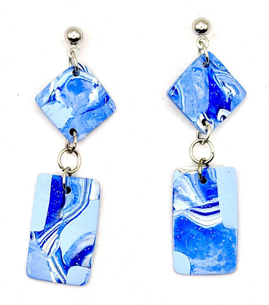 A pair of drop earrings featuring marbled blue and white glass pieces with silver-tone metal findings, shown against a plain white background.