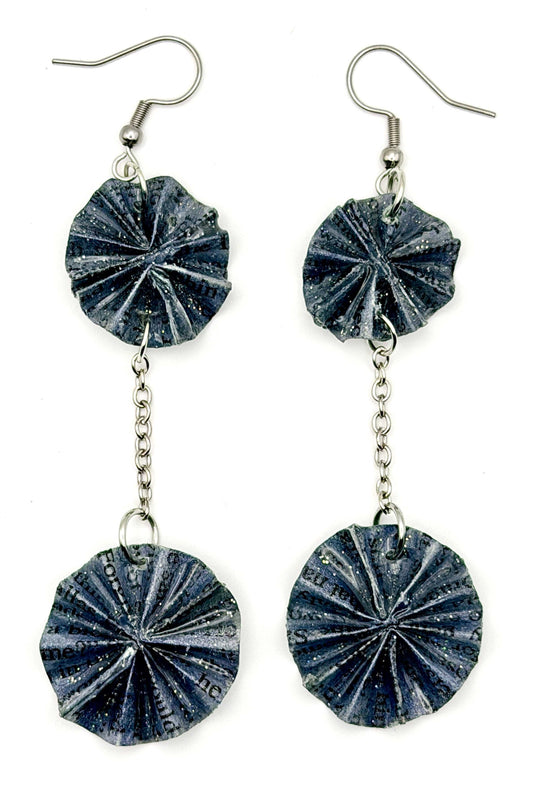 A pair of handmade dangle earrings featuring textured, dark blue-gray paper disc charms with a radial pleated pattern, suspended from silver-tone wire hooks and chain links, shown against a plain white background.
