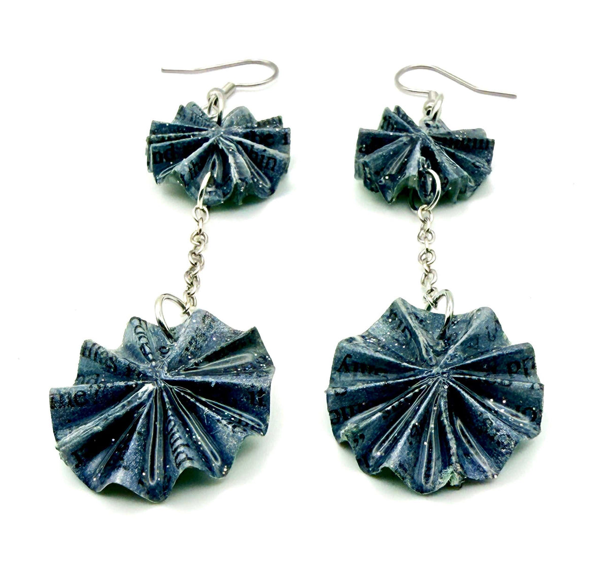 A pair of handmade dangle earrings featuring textured, fan-shaped silver-toned discs with a blue and white pattern, suspended by short chains from matching hooks on a white background.