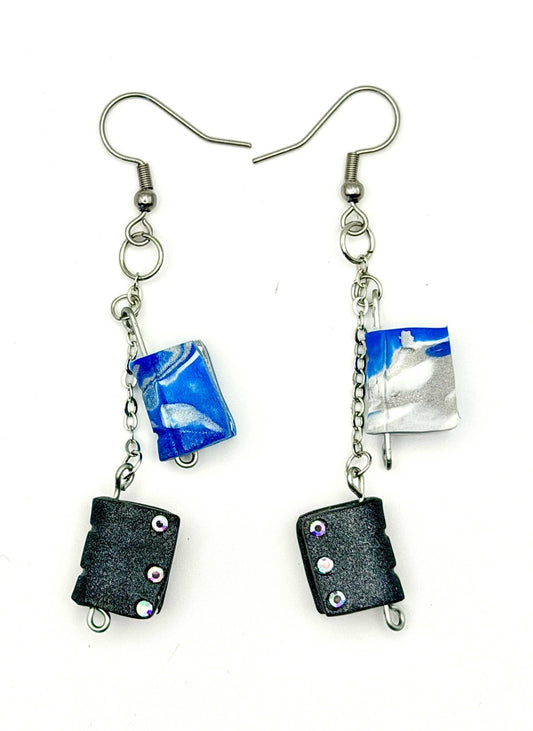 Handmade statement earrings featuring grey and blue books, attached to silver chains and hooks.