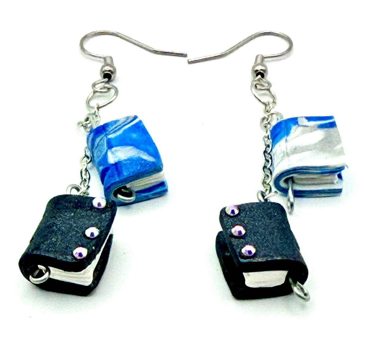 Close-up of grey and blue book earrings with chain links and silver hooks, showcasing unique book design and adorned with rhinestones.