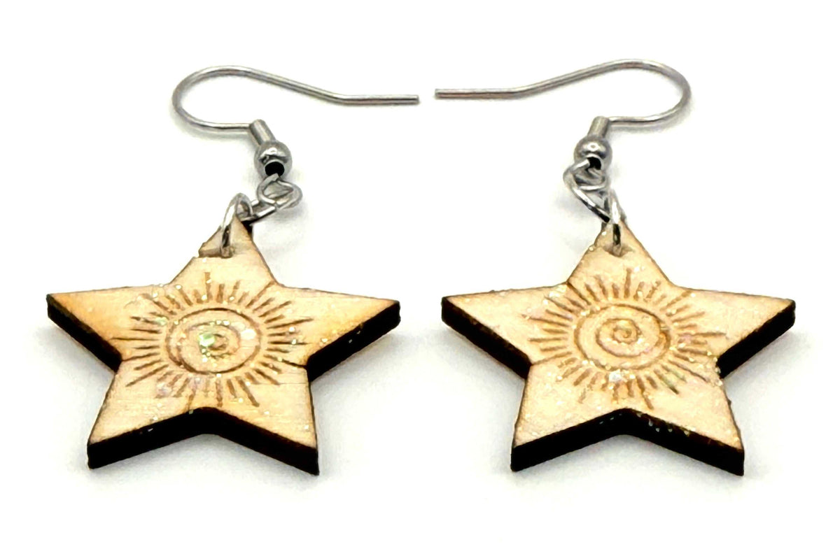 Close-up of laser cut and engraved wood earrings with silver hooks, showcasing a unique spiral design and glitter accents