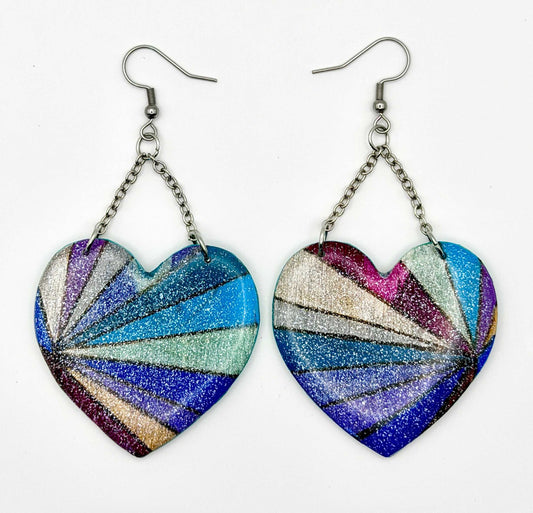 Handmade statement earrings featuring a hand painted multi-colored design, attached to silver chains and hooks.