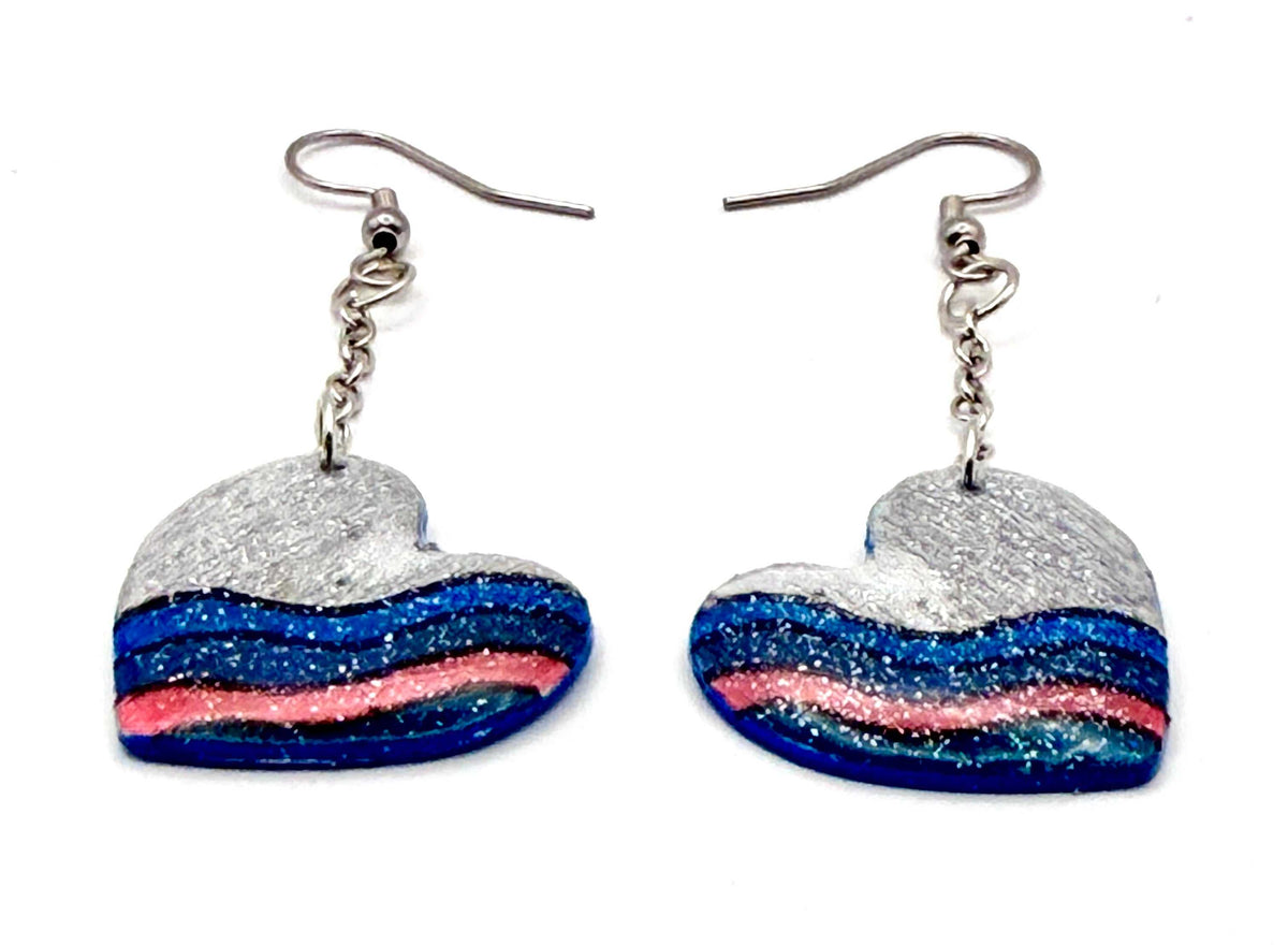 Close-up of grey heart earrings with chain links and silver hooks, showcasing unique hand painted design.