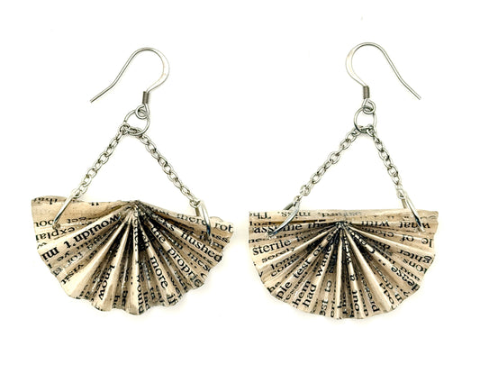 A pair of handmade dangle earrings featuring fan-shaped paper charms printed with black book text, suspended from silver-tone chains and hooks against a plain white background.