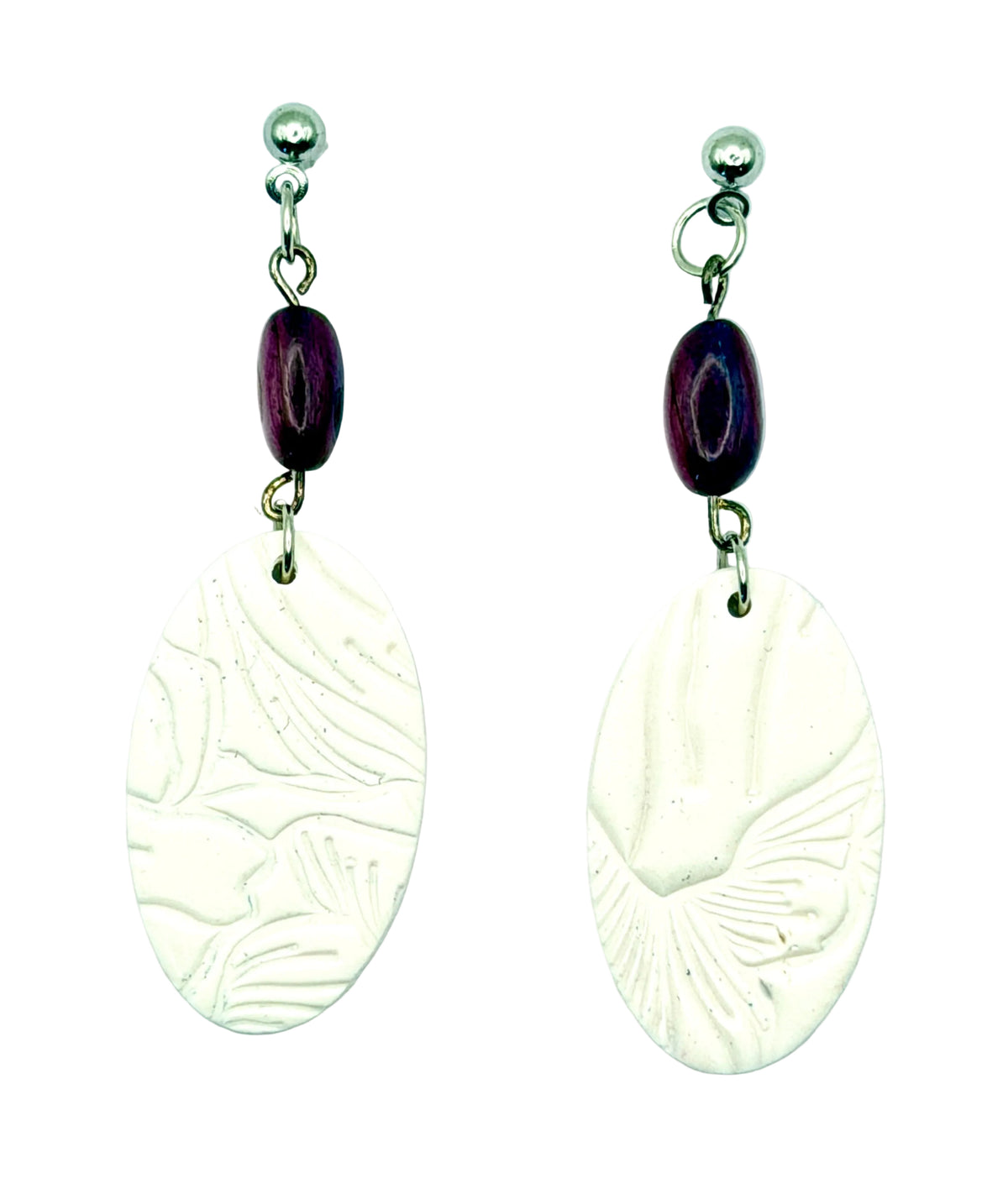 A pair of handmade dangle earrings featuring oval white textured clay pendants and dark purple beads on silver-toned posts, set against a plain light blue background.