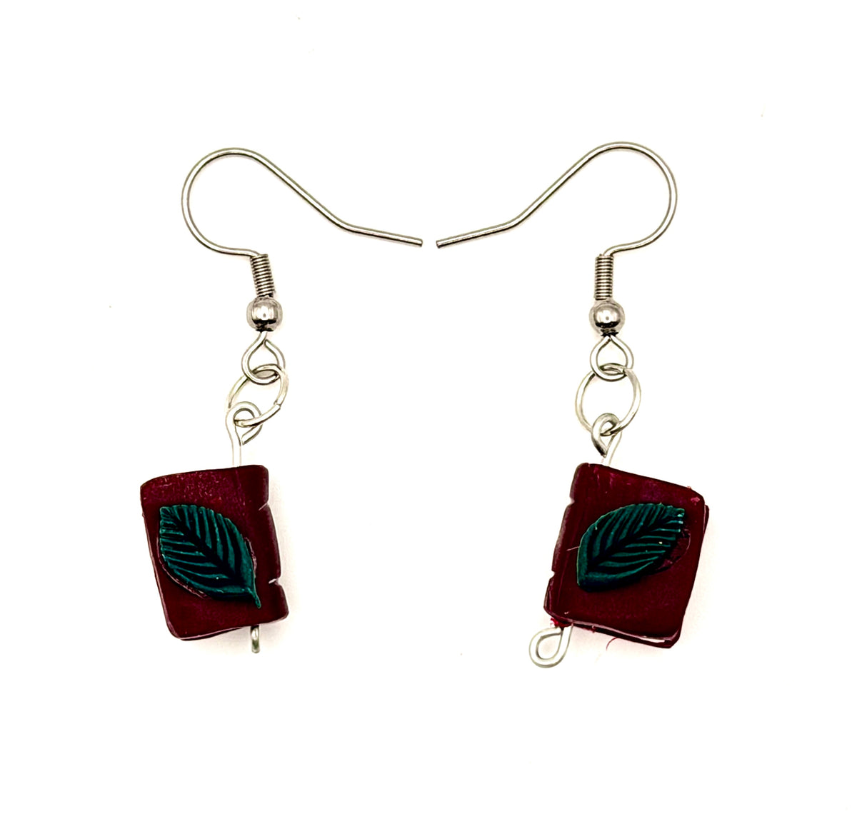 Maroon polymer clay book earrings with a green leaf on top. Suspended by a metal fishhook ear wire.
