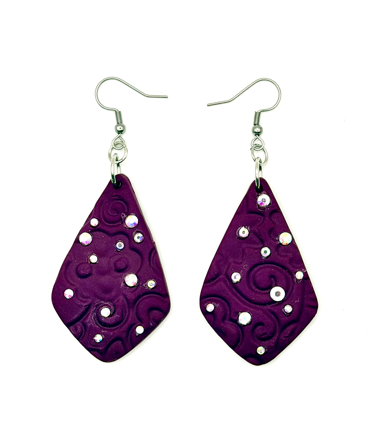 A pair of diamond-shaped purple/red polymer clay dangle earrings with embossed swirl patterns and small silver and clear rhinestone embellishments, hanging from silver fishhook wires on a white background.