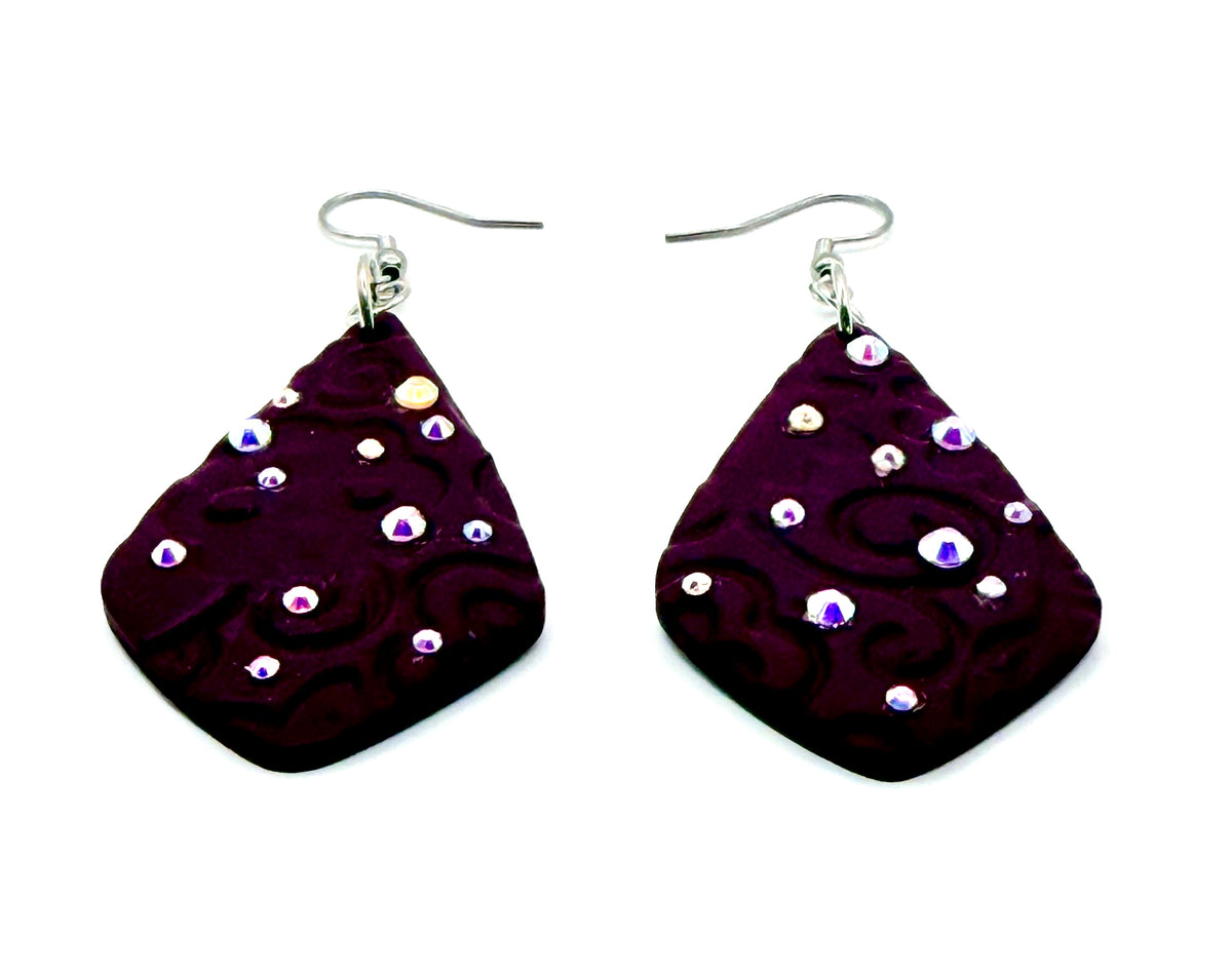A pair of teardrop-shaped dark purple/red polymer clay earrings with a swirled pattern and small iridescent rhinestones, hanging from silver fishhook wires on a white background.