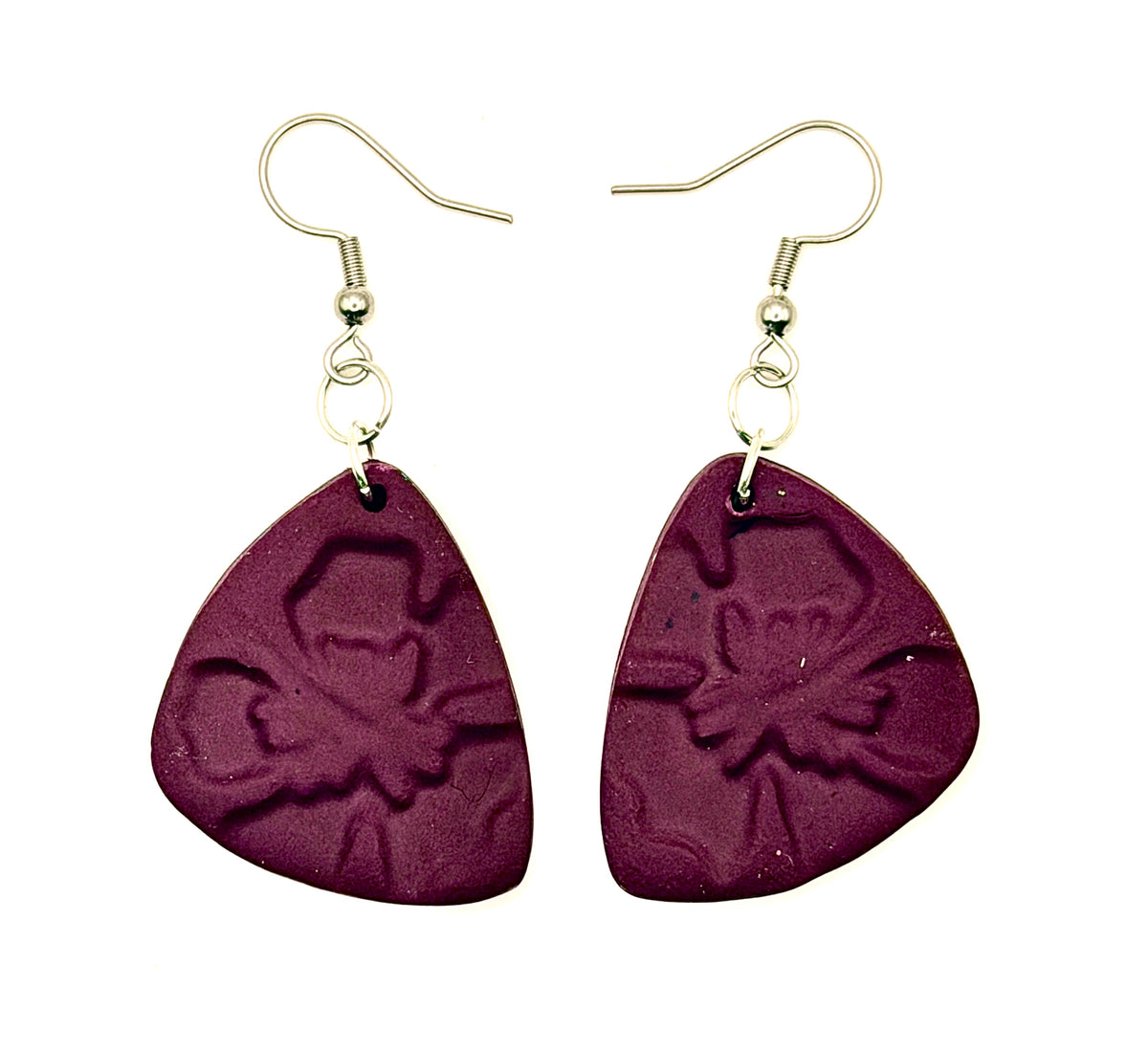 A pair of handmade dangle earrings featuring triangular purple polymer clay pieces embossed with a floral pattern, suspended from metal fishhook wires on a plain white background.